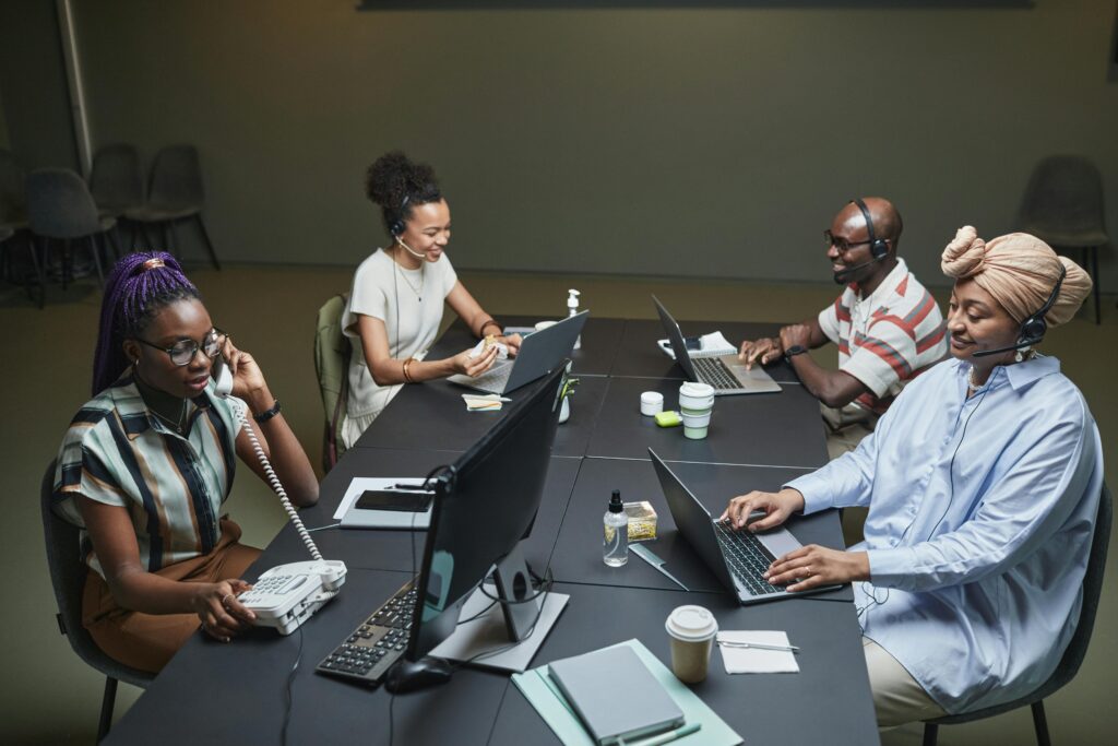 Diverse call center team working collaboratively with technology and headsets in a modern office setting.